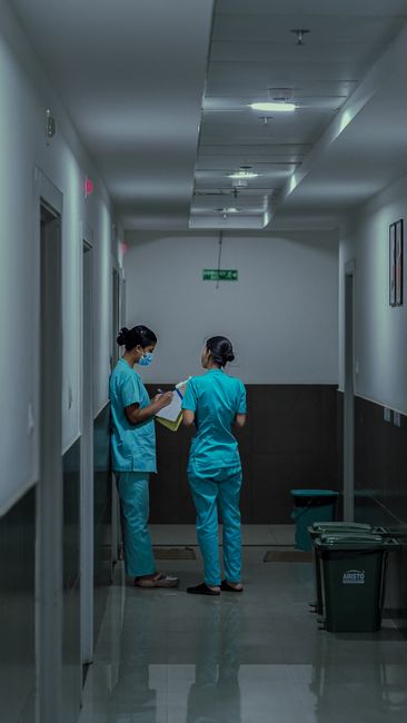 Asian nurses in hospital corridor discussing patient care