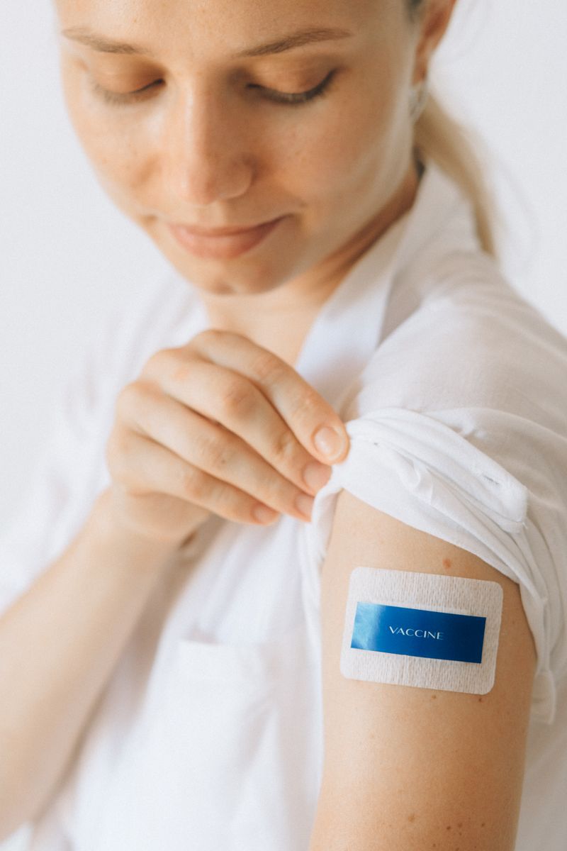 Woman showing vaccination bandage on arm after receiving hepatitis B vaccine